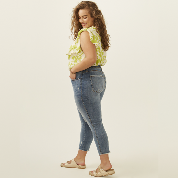 plus size woman in green and white floral printed sleeveless blouse and jeans with gold sandals