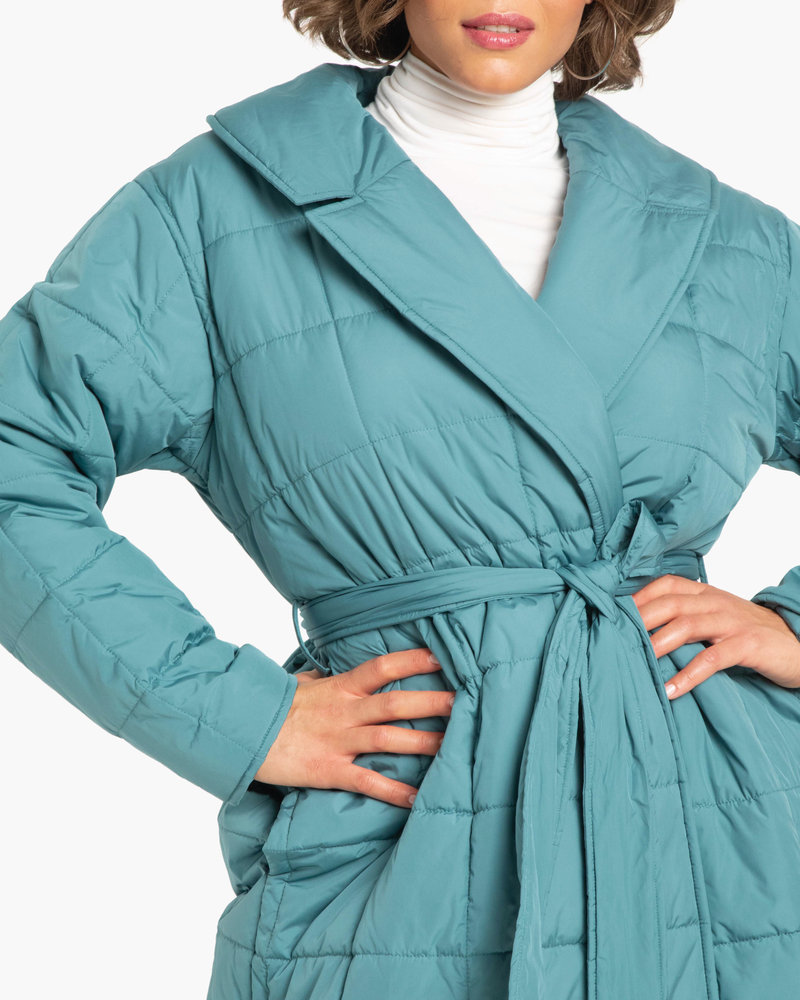 plus size woman in teal puffer jacket and white turtleneck